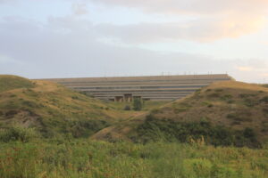 An image of the University Hall building of the University of Lethbridge situated within the "coulee" hills in Lethbridge, shown in a moment when the sun is setting.
