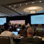 A CAUT council meeting in progress at the Delta Hotel Ottawa City Centre, with attendees engaged in discussions and using laptops.